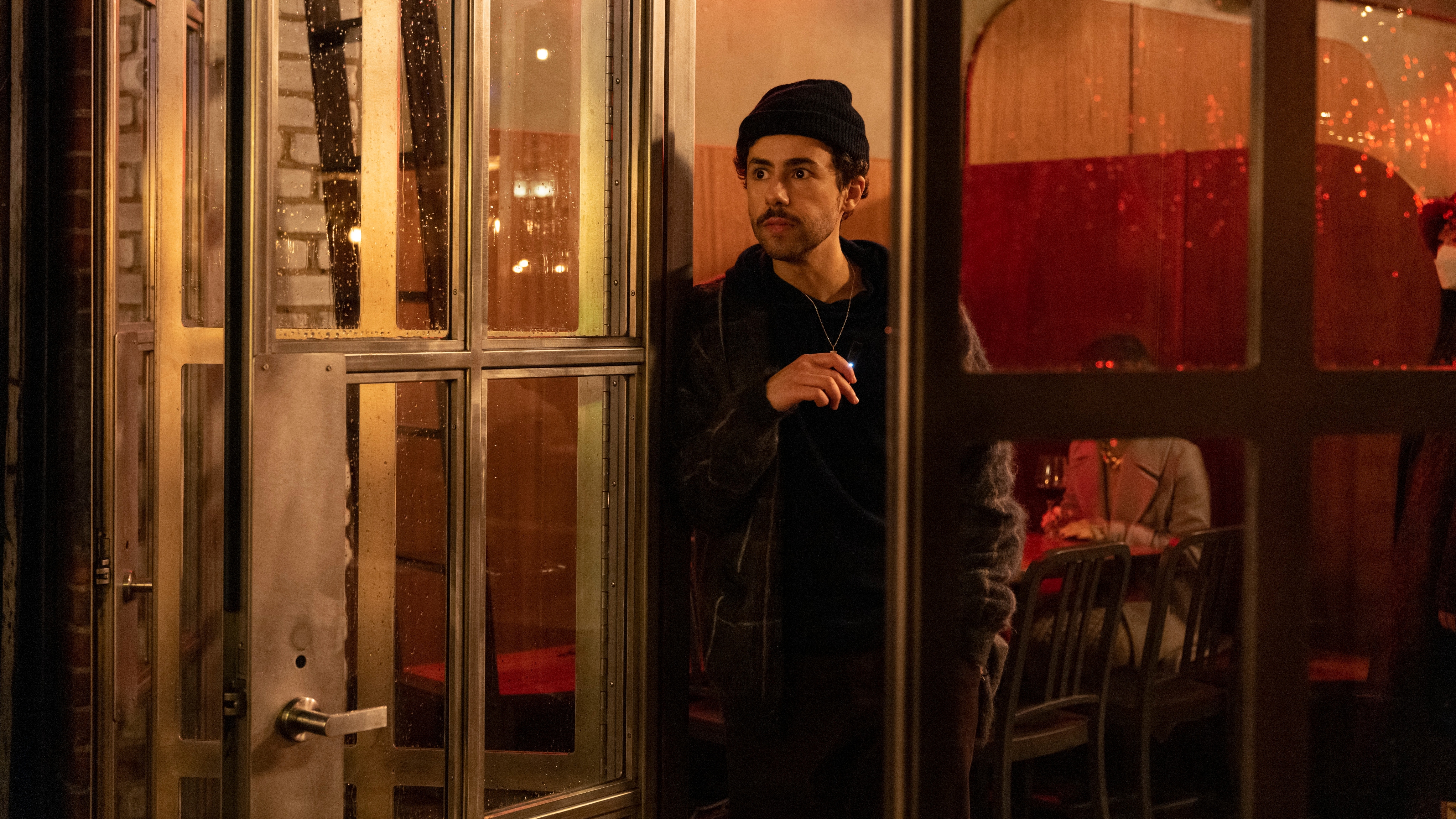 Ramy Youssef standing at a glass door in Ramy season 3.