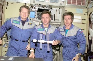 Expedition 1 crewmates Bill Shepherd, Yuri Gidzenko and Sergei Krikalev pose with a model of the space station as it appeared in 2000.