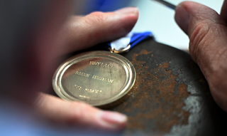 A close up of the engraving of Brian Harman's gold medal he won in 2023