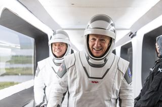NASA astronauts Doug Hurley (center) and Bob Behnken smile as they walk across the Crew Access Arm to their Crew Dragon spaceraft during a launch attempt at NASA's Kennedy Space Center in Florida on May 27, 2020.