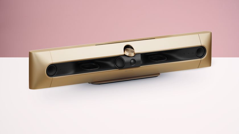 The Bang &amp; Olufsen Beosound Premiere in a gold finish, on a white surface against a pink background