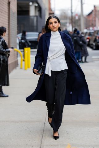 A woman at fashion week with a long coat and twisted top