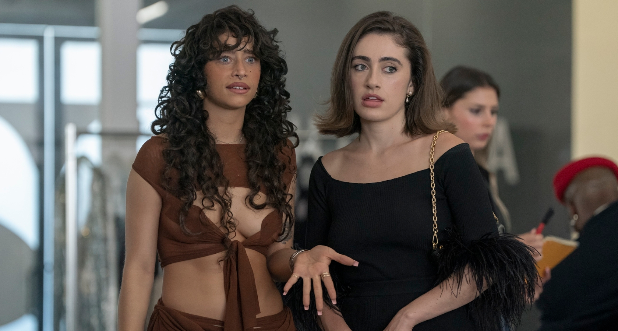 odessa a'zion as tallulah wearing a brown cut out set and rachel sennott as maia wearing a black feather top in an office for a fashion designer in a still from the i love la season 1 finale