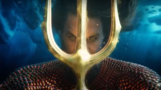 A screenshot of Arthur Curry holding his trident in front of his face in Aquaman 2