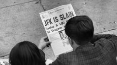 25th November 1963: Two people in Lafayette Park, Washington, reading the newspaper reports of President John F Kennedy's assassination.