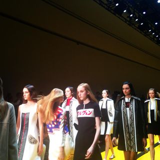 Models on the runway wearing dresses, bombers and pointed collar car coats