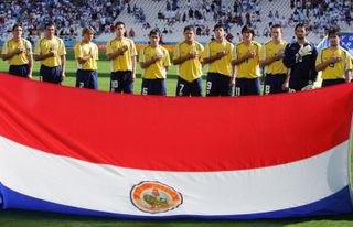 Paraguay players line up behind their national flag ahead of their Olympic football final against Argentina in August 2004.
