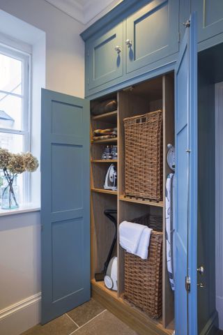 Floor to ceiling blue cabinets with shelving and storage baskets inside