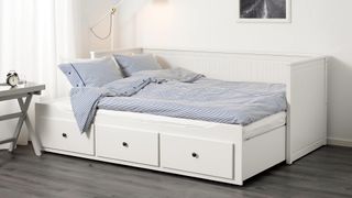 A white day bed with pull-out sleeping platform and storage drawers in a bedroom