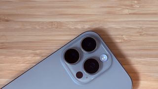 An iPhone 16 Pro on a wooden desk