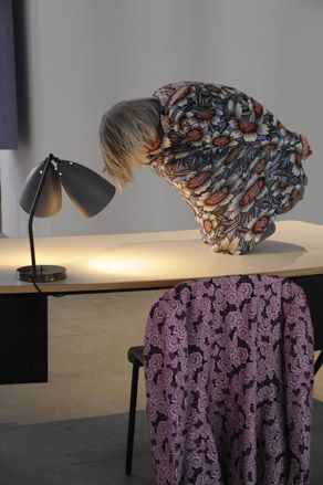 A female model crouched on top of a table in a floral outfit with no legs