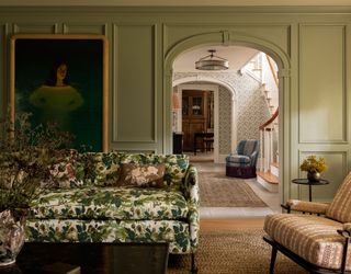 A living room with a couch in green printed upholstery, and walls painted a watery blue