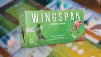 Wingspan Americas Expansion box over a blurred image of the Wingspan board and pieces laid out on a table