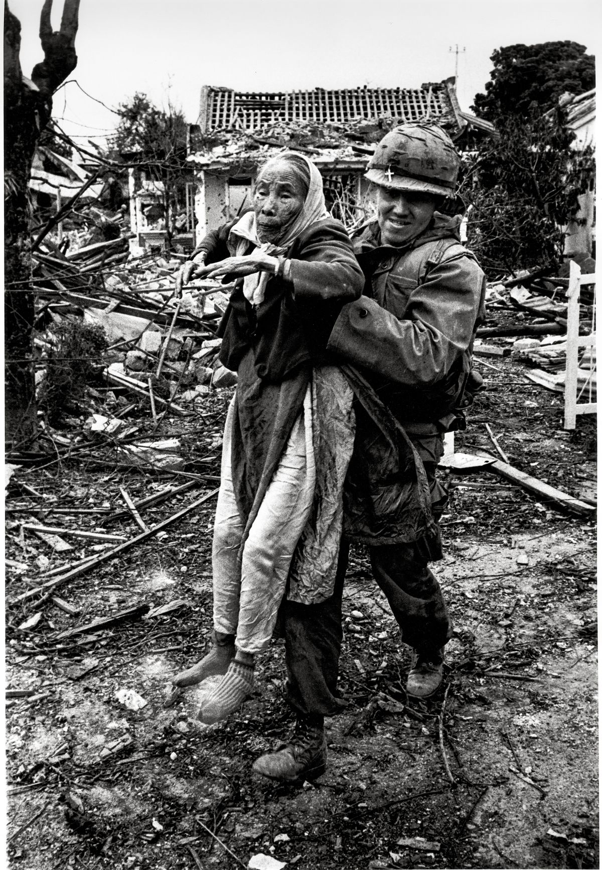 A solider carries a person through rubble, Vietnam
