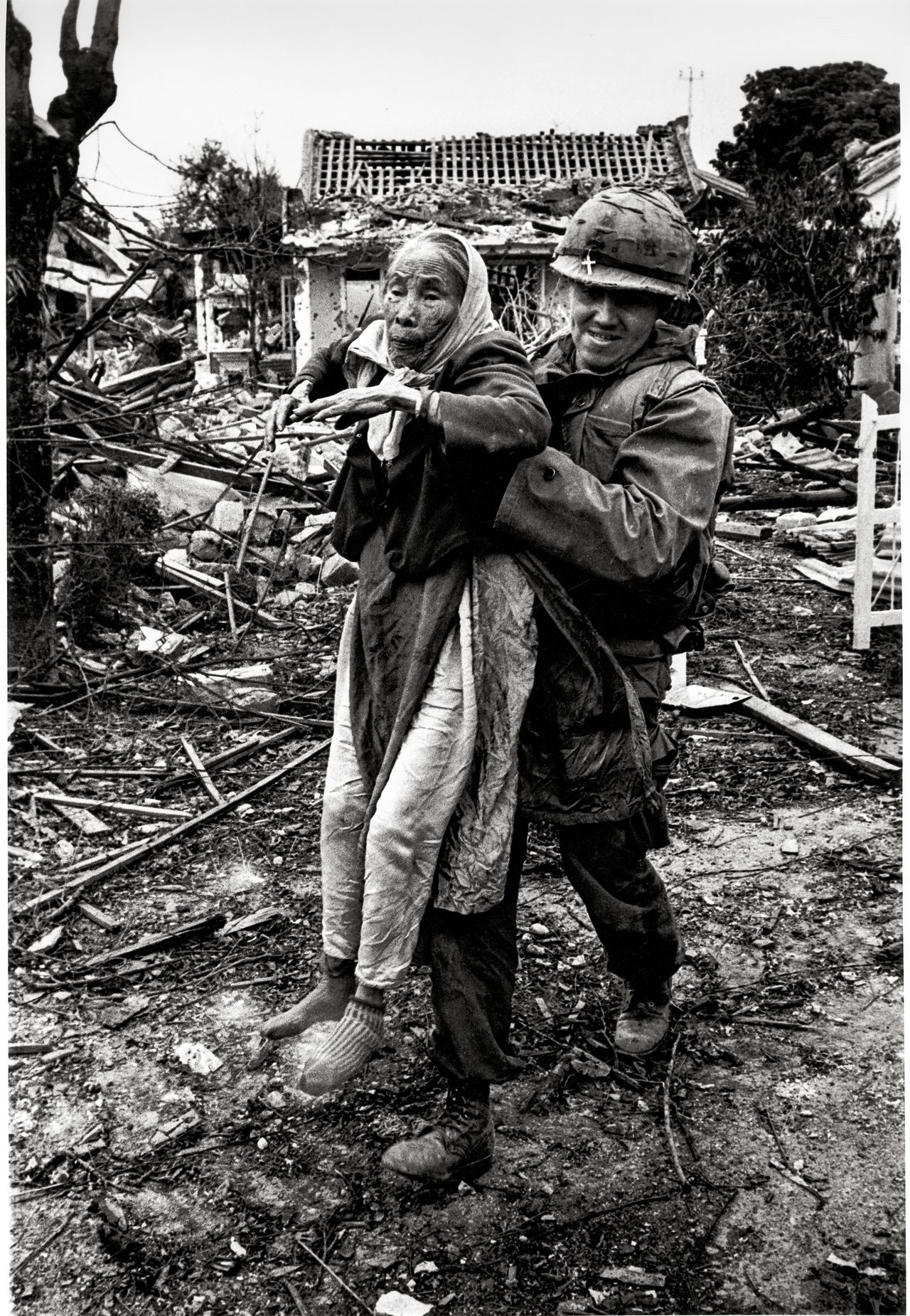 A solider carries a person through rubble, Vietnam