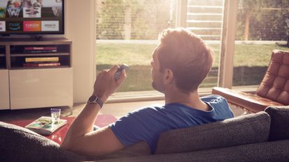 man sat on sofa watching television using amazon fire stick smart streamer by amazon