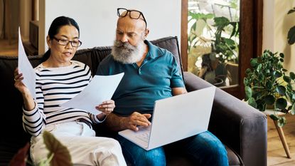 An older couple sit on the sofa with a laptop to look at their retirement planning.