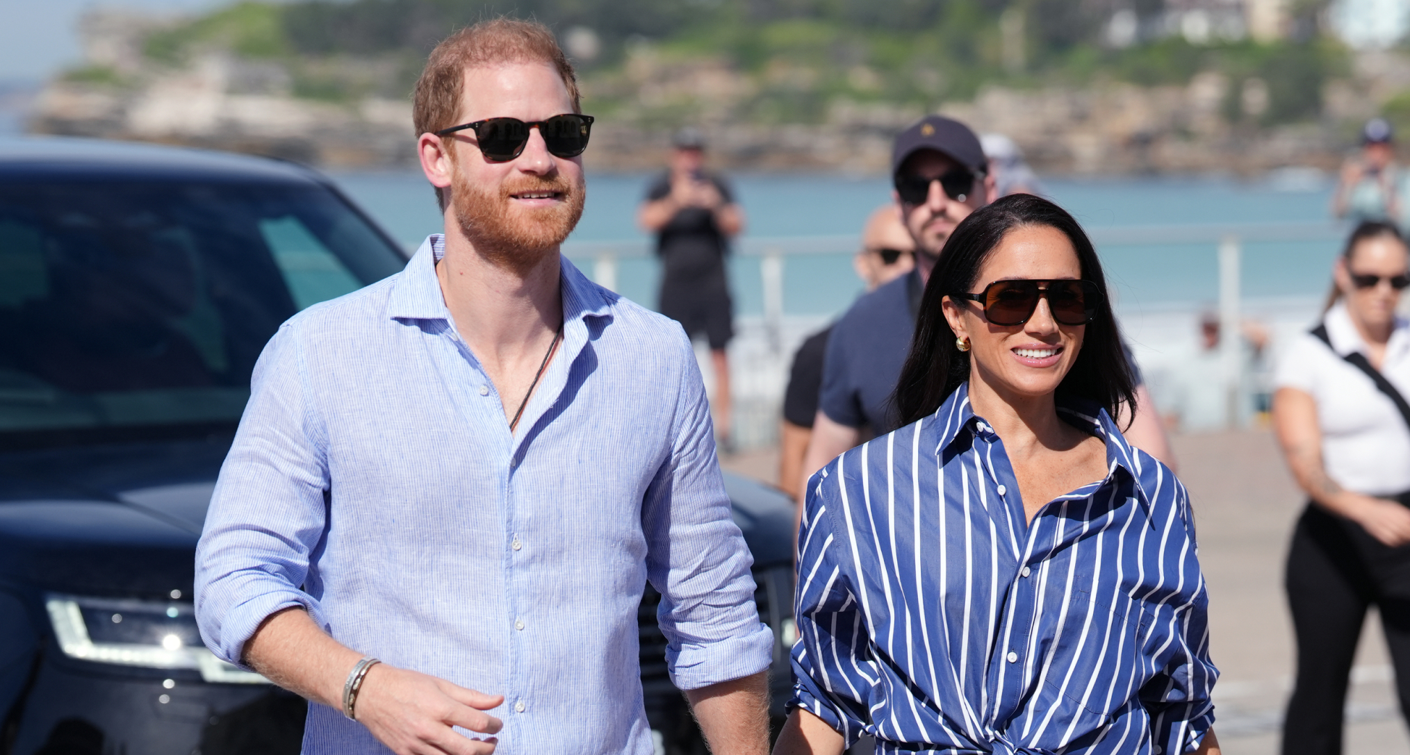 Prince Harry and Meghan Markle wearing sunglasses walking outside