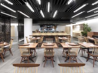 Pictured is the Akira restaurant which features eight two-seater wooden tables, two four seater wooden circular tables and a kitchen at work in the backdrop.