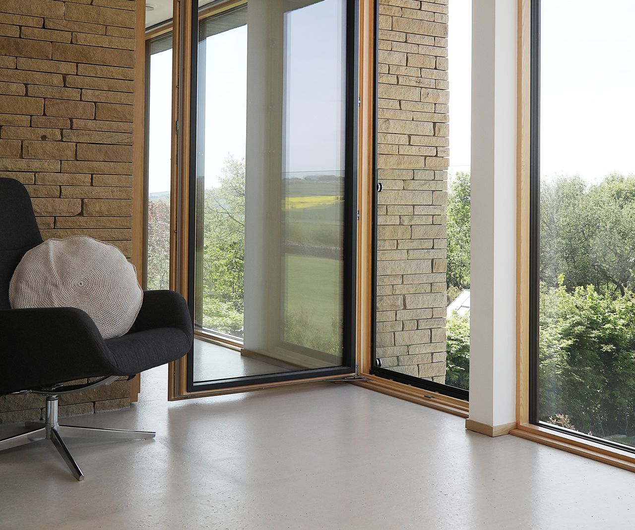 A panel of floor to ceiling glazing on a second floor landing is opened inward. There is a glass protective barrier at waist height which allows for people to stand at the window and look out in safety