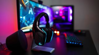 A Logitech G gaming headset on a desk in front of a gaming keyboard, mouse and monitor.