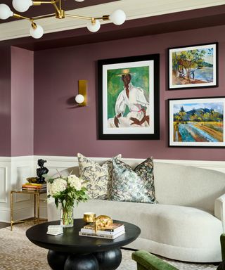 living room with purple walls, cream curved modern sofa, black round coffee table, colorful artwork on walls