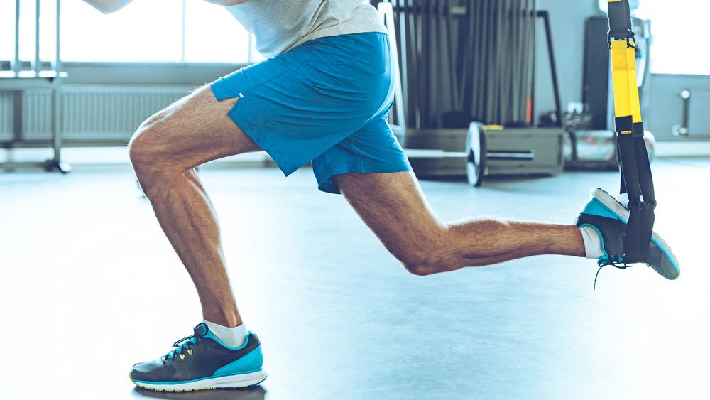 Man in shorts performing TRX split squat