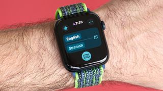 Close-up photo of an Apple Watch SE 2022 against a red background with the new Translate app displayed on the screen