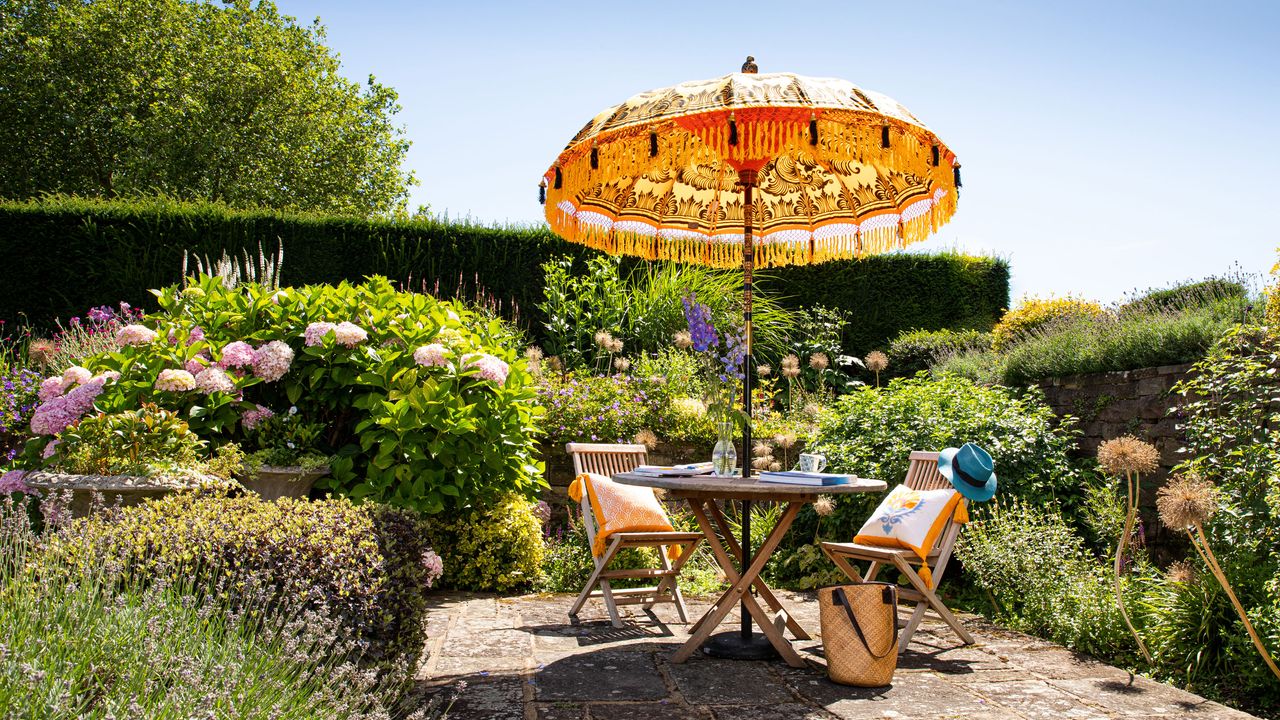 Roost episode 2 - patio with fringe parasol and outdoor furniture in large garden - Pic-credit-East-London-Parasol-Company