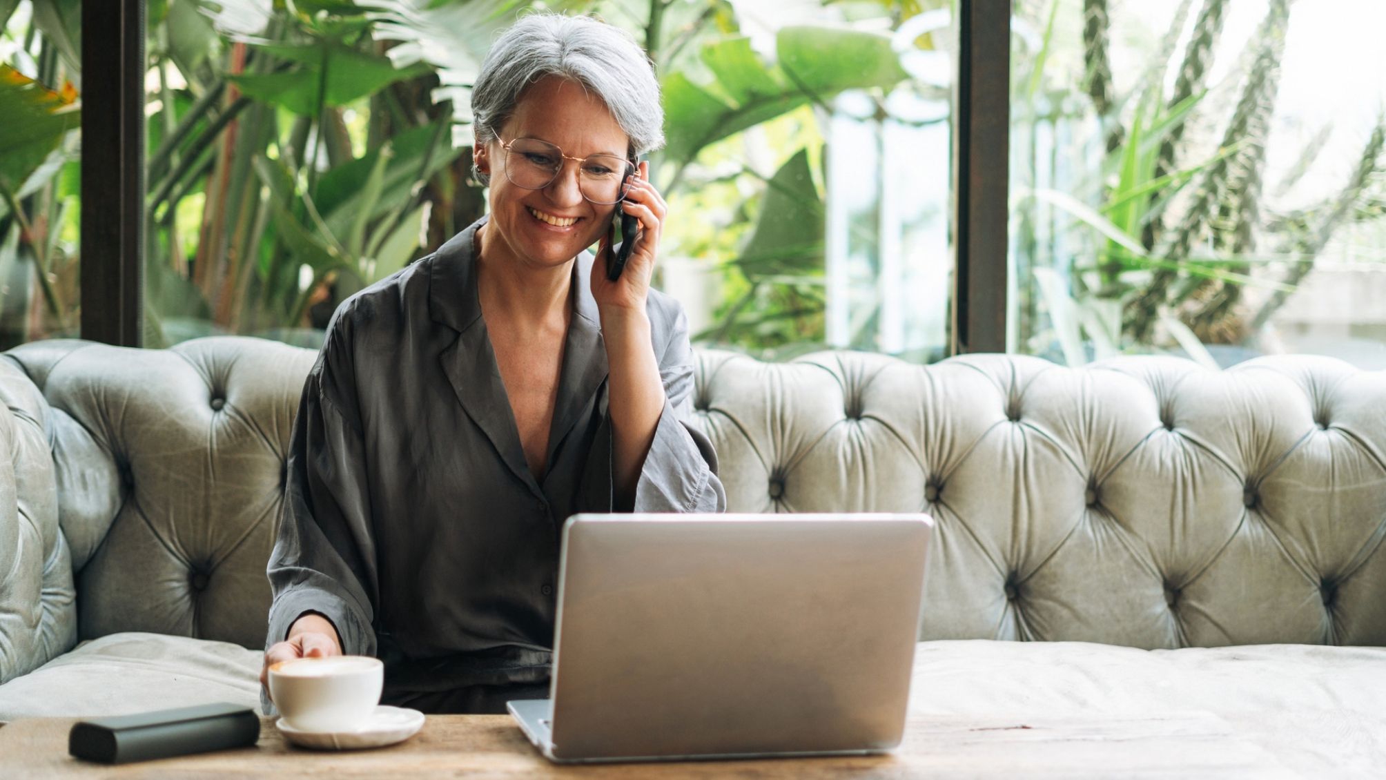 A woman is talking on the phone while working on her laptop. 