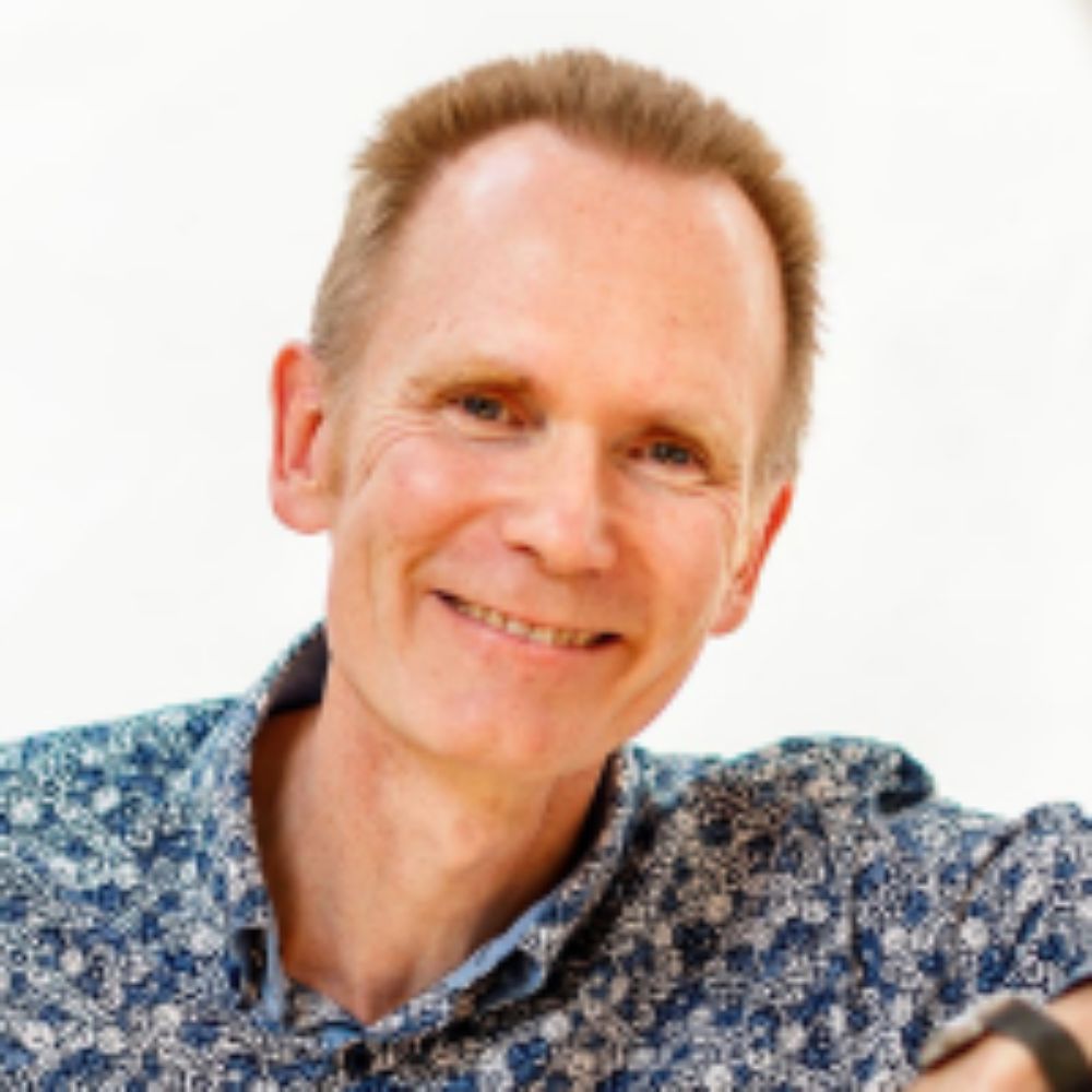 Headshot of a man in a blue floral shirt