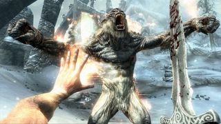 Skyrim - A player holds a sword and casts a fire spell at a troll.