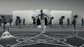 A bloodied Tyriq Withers stands ominously on a football field with a heartagram in Him.