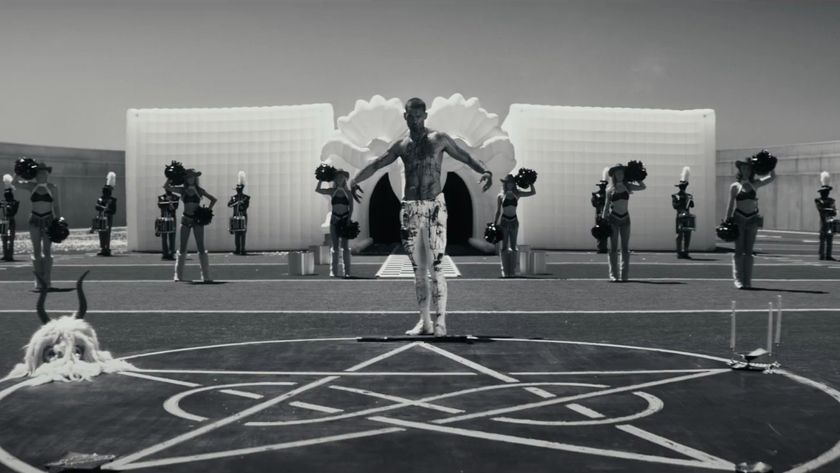 A bloodied Tyriq Withers stands ominously on a football field with a heartagram in Him.