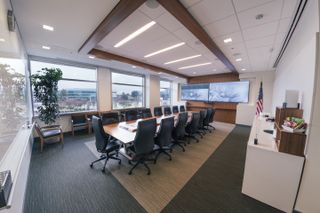The standardized videoconferencing room setups at Juniper include dual Samsung displays, Polycom videoconferencing equipment, Shure microphones, and Crestron control.
