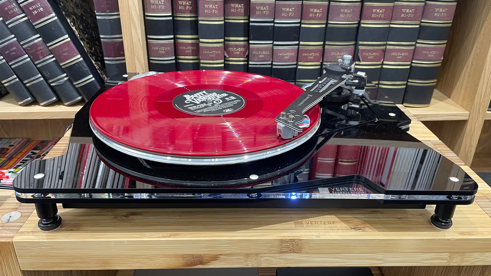 Vertere DG-X turntable in front of bookcase playing pink vinyl record