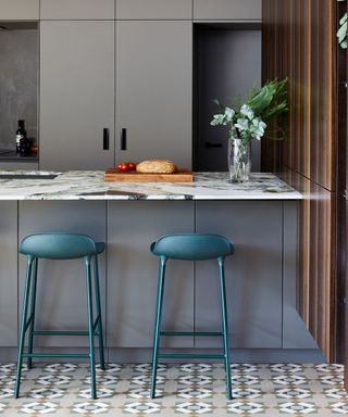 Gray kitchen with petrol blue bar stools and patterned floor tiles