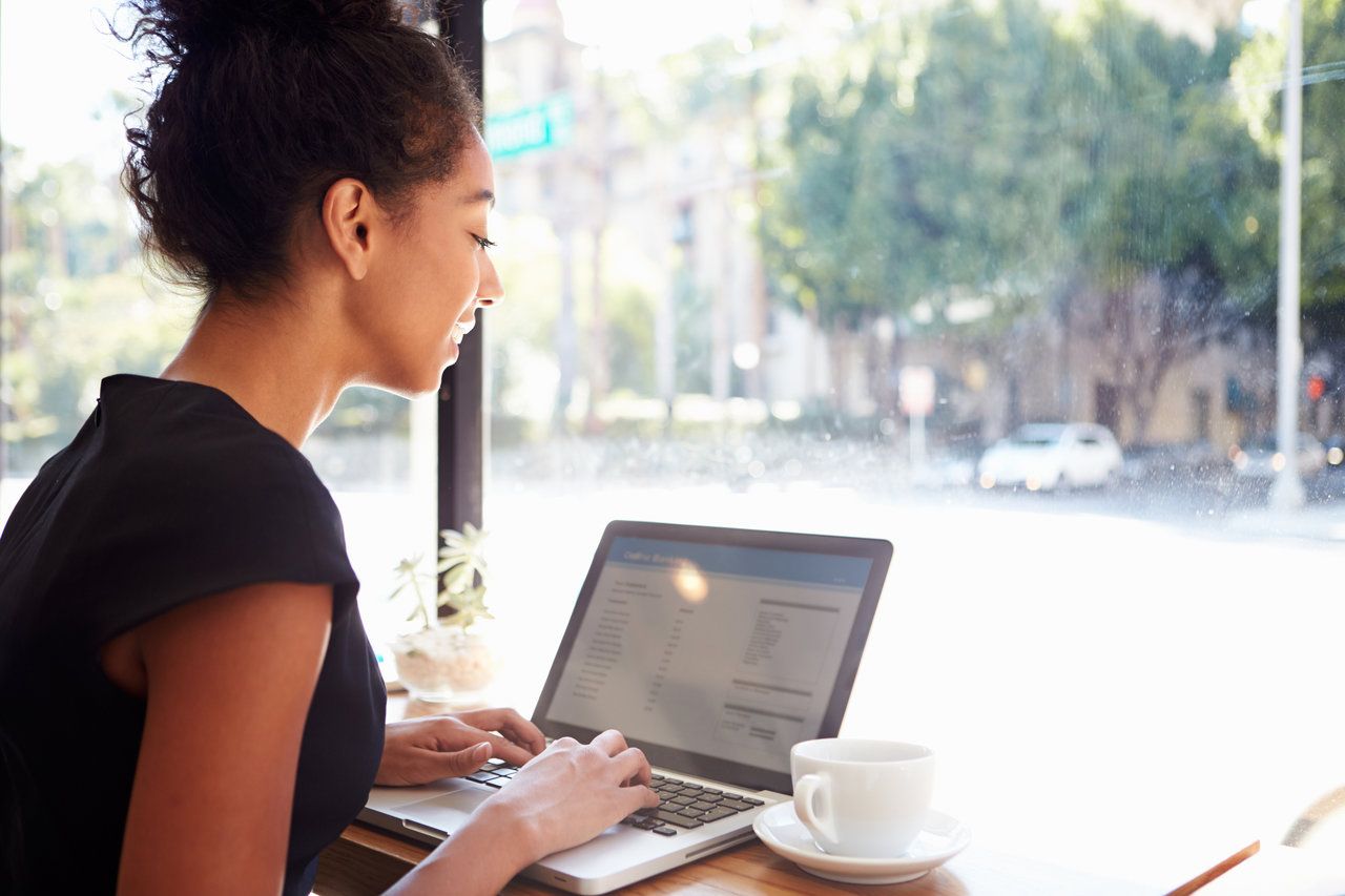 Businesswoman Working Using Laptop In Coffee Shop