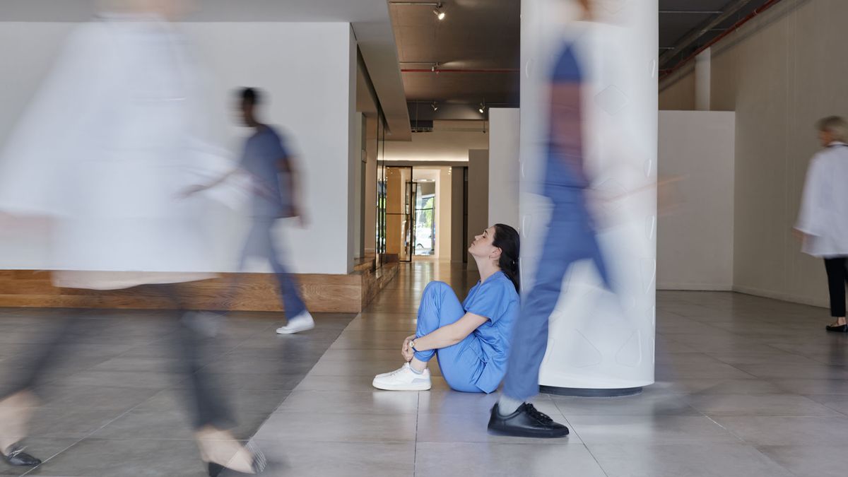 Shot of a young female doctor looking tired while working in a busy hospital 