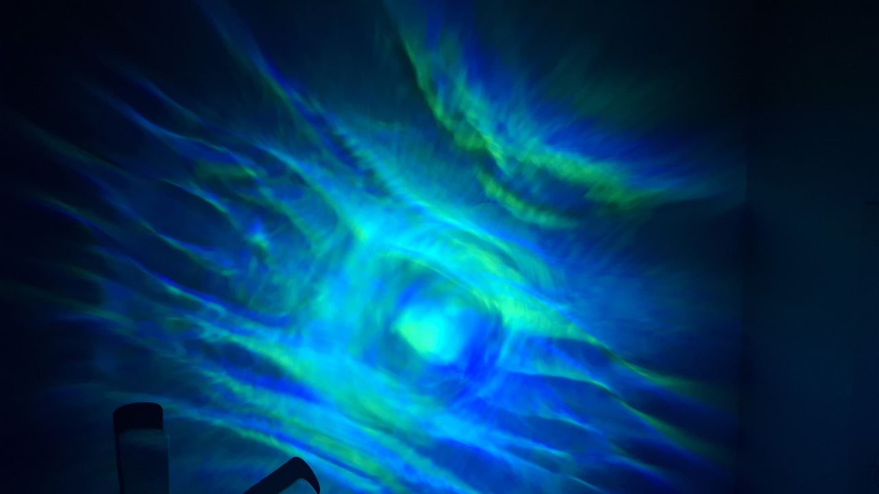 A blue projection is on a wall in a dark room.