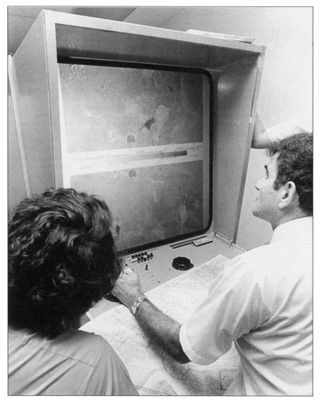 Scientists in 1972 viewing a Landsat enlargement on a special machine in the control center.