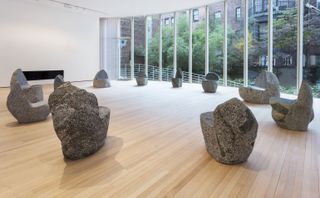 Max Lamb’s ‘Boulders’ collection of stools and chairs on wooden floor in room with many aluminium doors