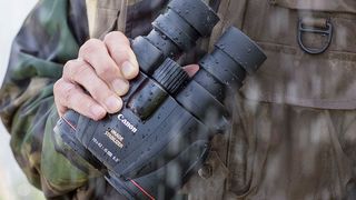 Canon 10x42L IS WP binoculars being held against the body in the rain
