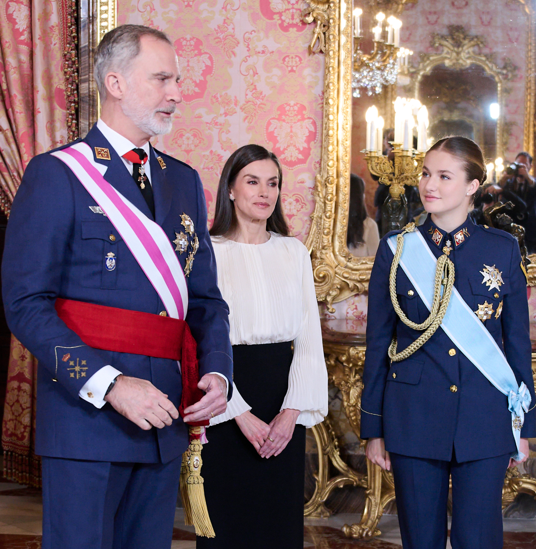 King Felipe and Princess Leonor wearing military uniforms standing with Queen Letizia in a white top and black pants