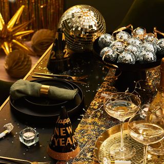 A table decorated with a centrepiece bowl filled with mirrored baubles and string lights