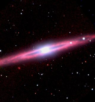 The nearly edge-on galaxy NGC 5746 is partially obscured in visible-light photographs, making accurate classification impossible. This image from the Spitzer Space Telescope reveals the galaxy's true nature, showing a dramatic ring of warm dust surrounding the galaxy's bright nucleus.