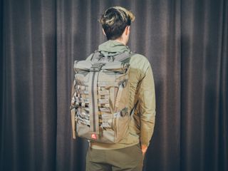 Will Jones, wearing the Chrome Barrage, one of the best backpacks for cycling, stands in front of a wall