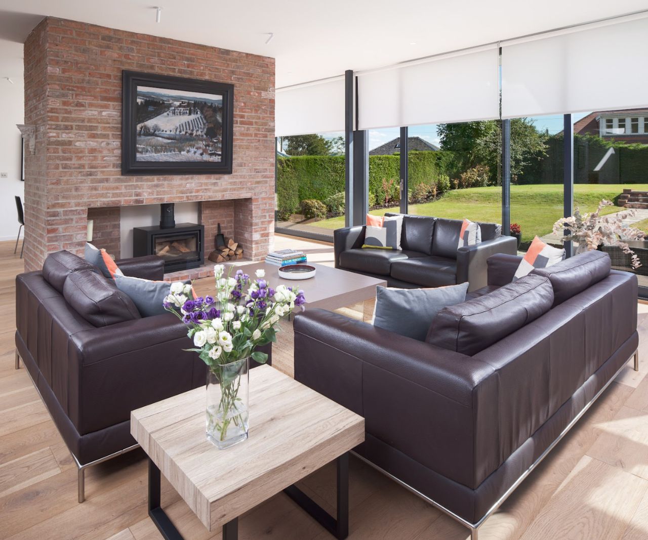 A contemporary lounge with a brick fireplace and leather sofas