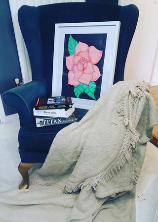 blue velvet arm chair with books and painting