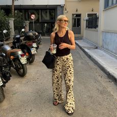 fashion influencer Lucy Williams in Europe wearing printed pants, a black tank, and sunglasses